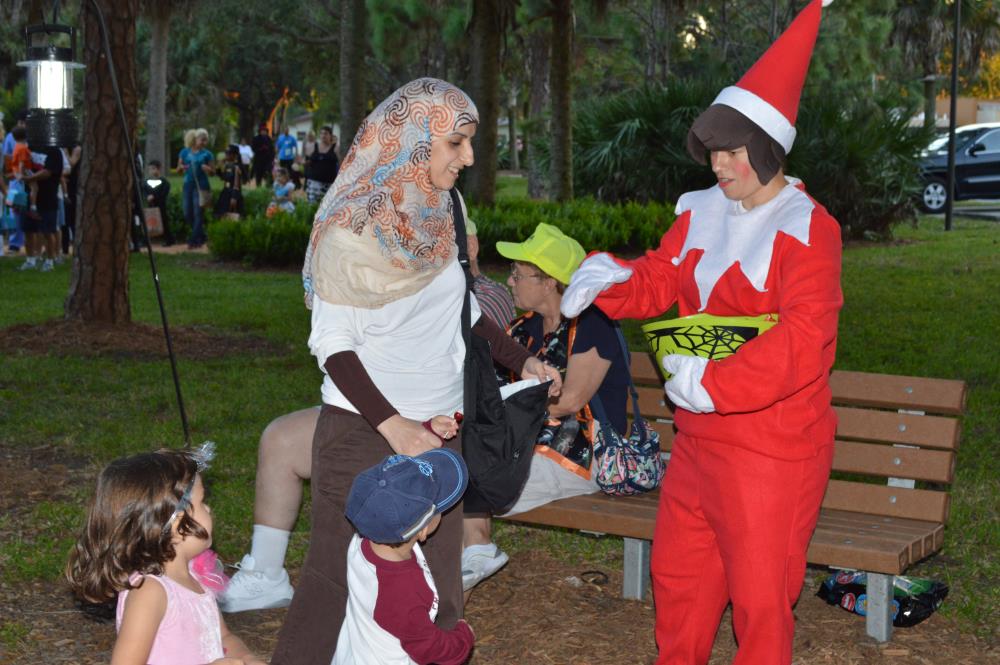 Woman in red elf costume hands out candy to kids